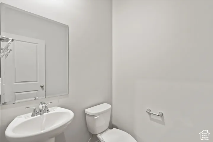 Pedestal sink featuring a dual-handle chrome faucet, wall-mounted mirror, and chrome hardware