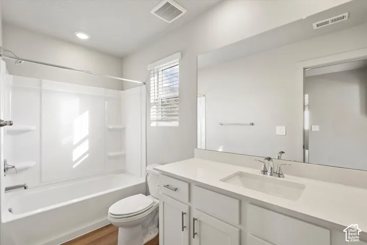 White cabinetry with chrome hardware, countertop with integrated sink, full-width vanity mirror, and tub-shower combination with surround