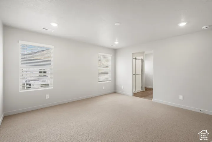 *DISCLAIMER* Interior color package may vary. Neutral-toned interior room with wall-to-wall carpeting, recessed ceiling lighting, two double-pane windows with horizontal blinds, and an entrance to a secondary space featuring a glass-enclosed shower