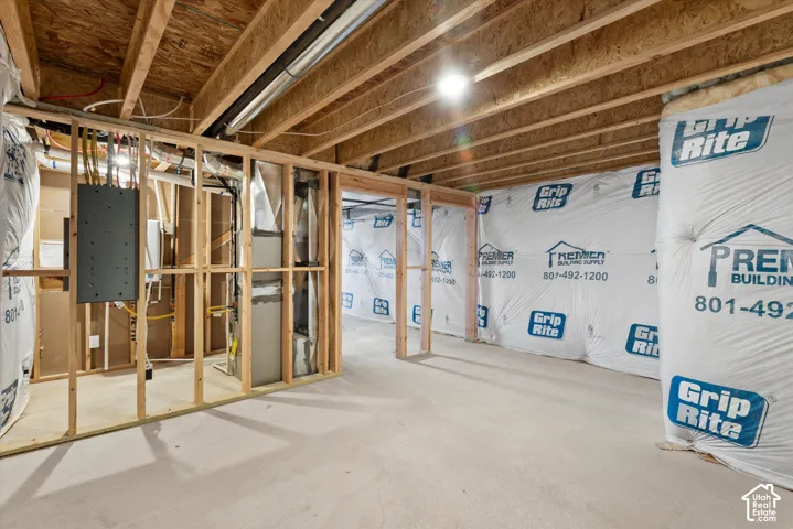 Unfinished basement featuring exposed wood-frame walls, concrete flooring, exposed ceiling joists, vapor-barrier insulation, and a mechanical area with a central HVAC unit