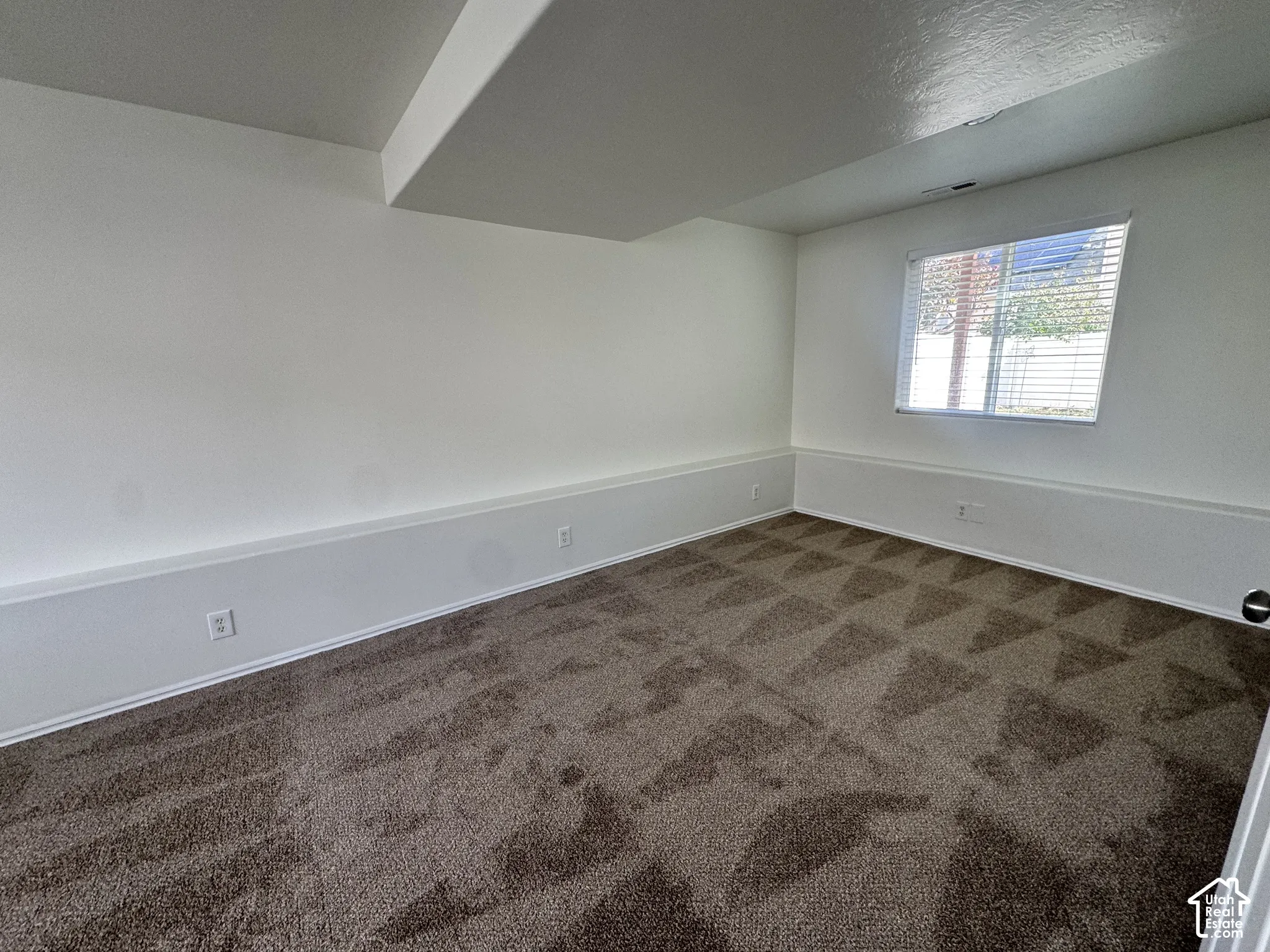 Neutral interior featuring wall-to-wall carpeting and a single-pane window with horizontal blinds