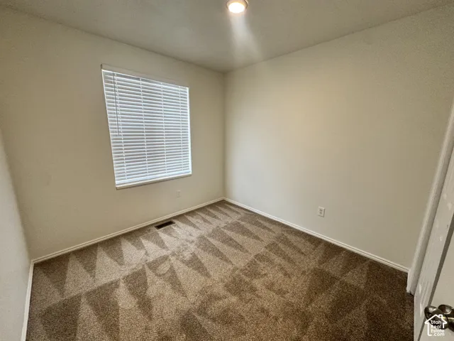 Neutral-toned carpeting, neutral wall paint, and horizontal window blinds with a flush-mount ceiling light fixture
