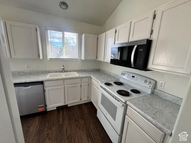Kitchen featuring white cabinetry, stone-patterned laminate countertops, wood-finish flooring, and built-in stainless steel and white appliances