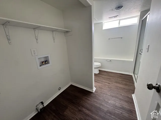 Laundry area featuring wood-finish flooring, a wall-mounted shelf, and dedicated water and electrical hookups