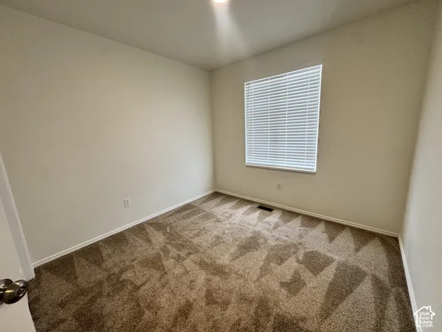 Neutral-toned wall paint, plush carpeting, and a window fitted with horizontal blinds