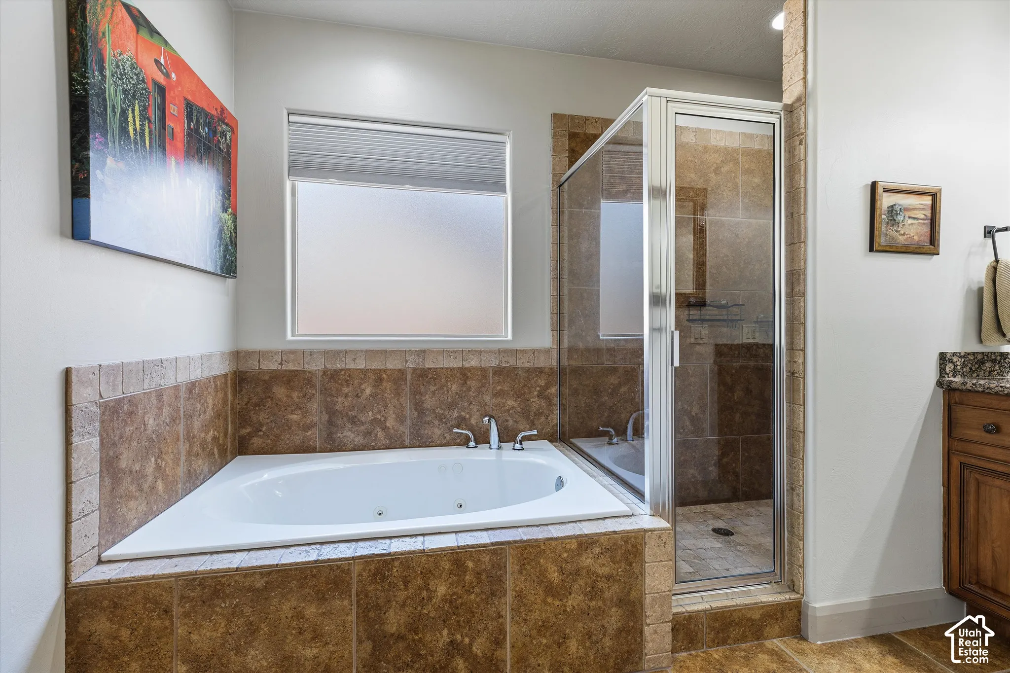 Bathroom featuring a jetted soaking tub, tiled surround, glass-enclosed shower, and built-in cabinetry