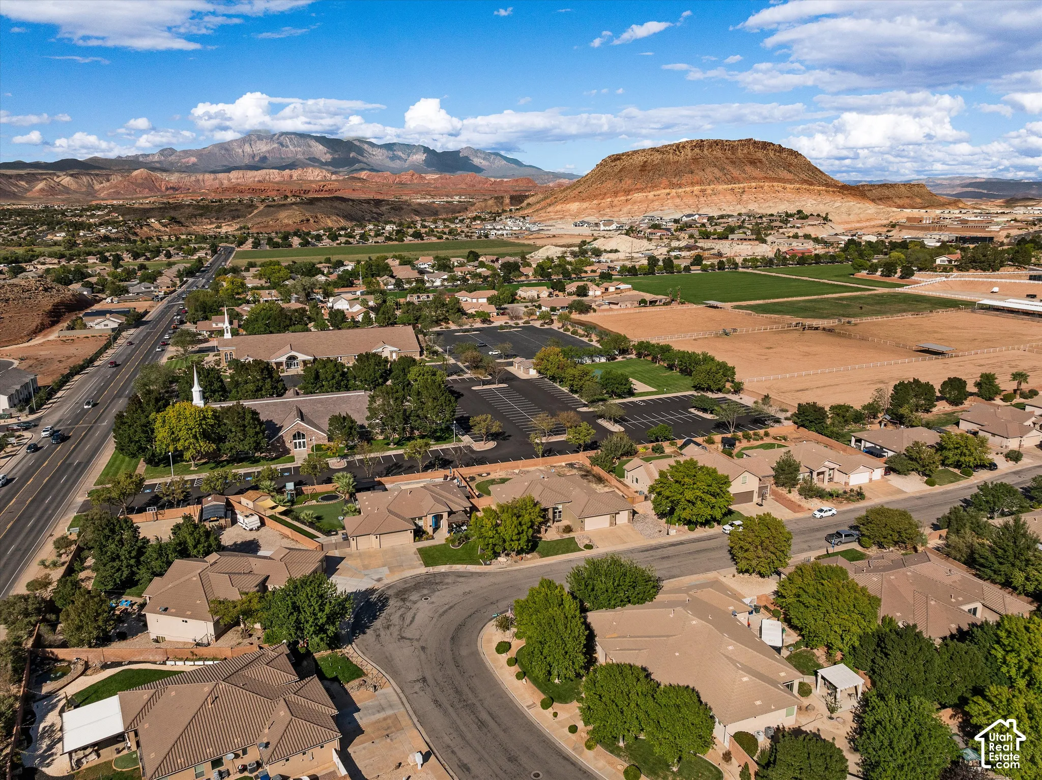 Aerial perspective featuring extensive desert terrain, prominent mountain topography, and established residential landscaping