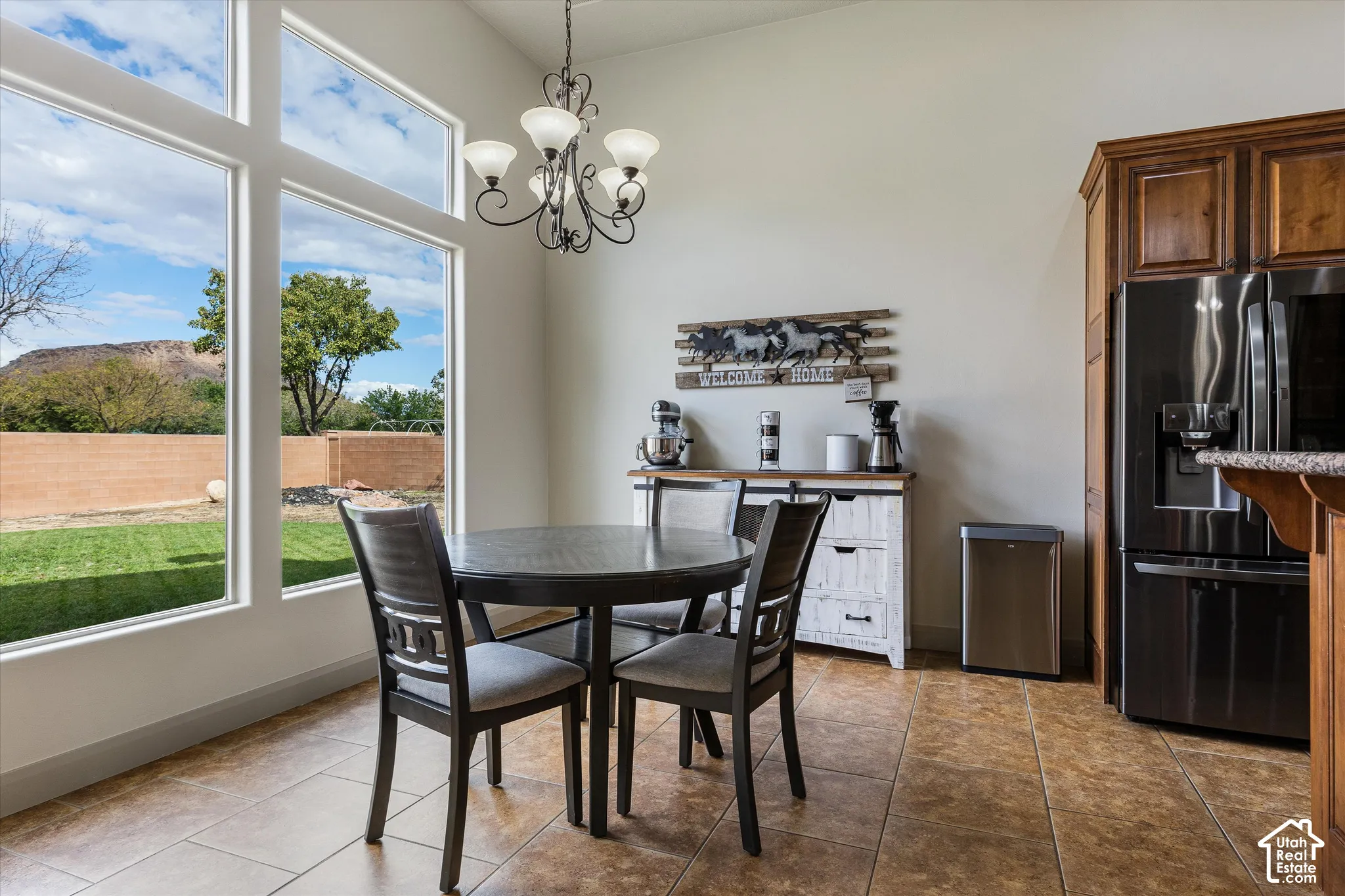 Floor-to-ceiling windows, tile flooring, ornate metal chandelier, and wood-finish cabinetry
