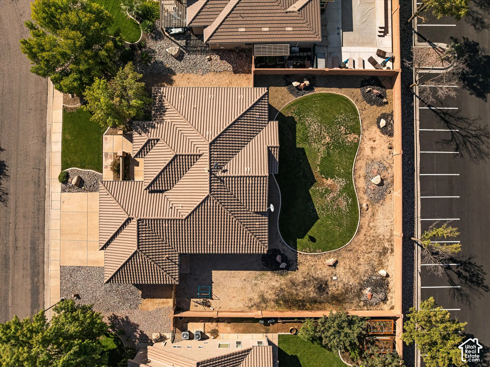 Aerial perspective featuring a tile roof, concrete driveway, fenced yard, lawn area, and gravel landscaping