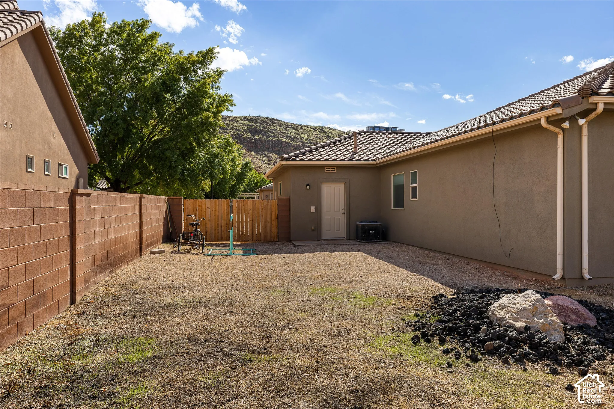 Side yard featuring a perimeter masonry block wall, gravel ground cover, wood privacy gate, and stucco exterior finish