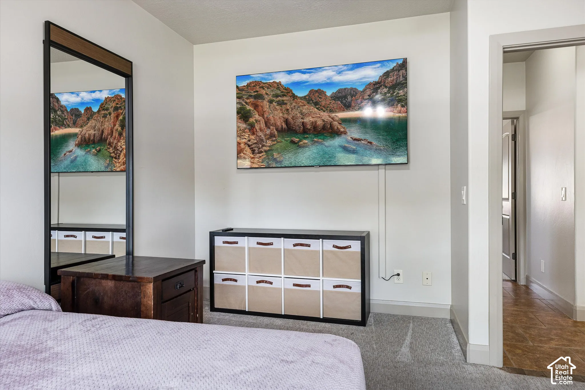 Wall-mounted mirror with a dark wood-finish frame, neutral wall paint, and grey wall-to-wall carpeting