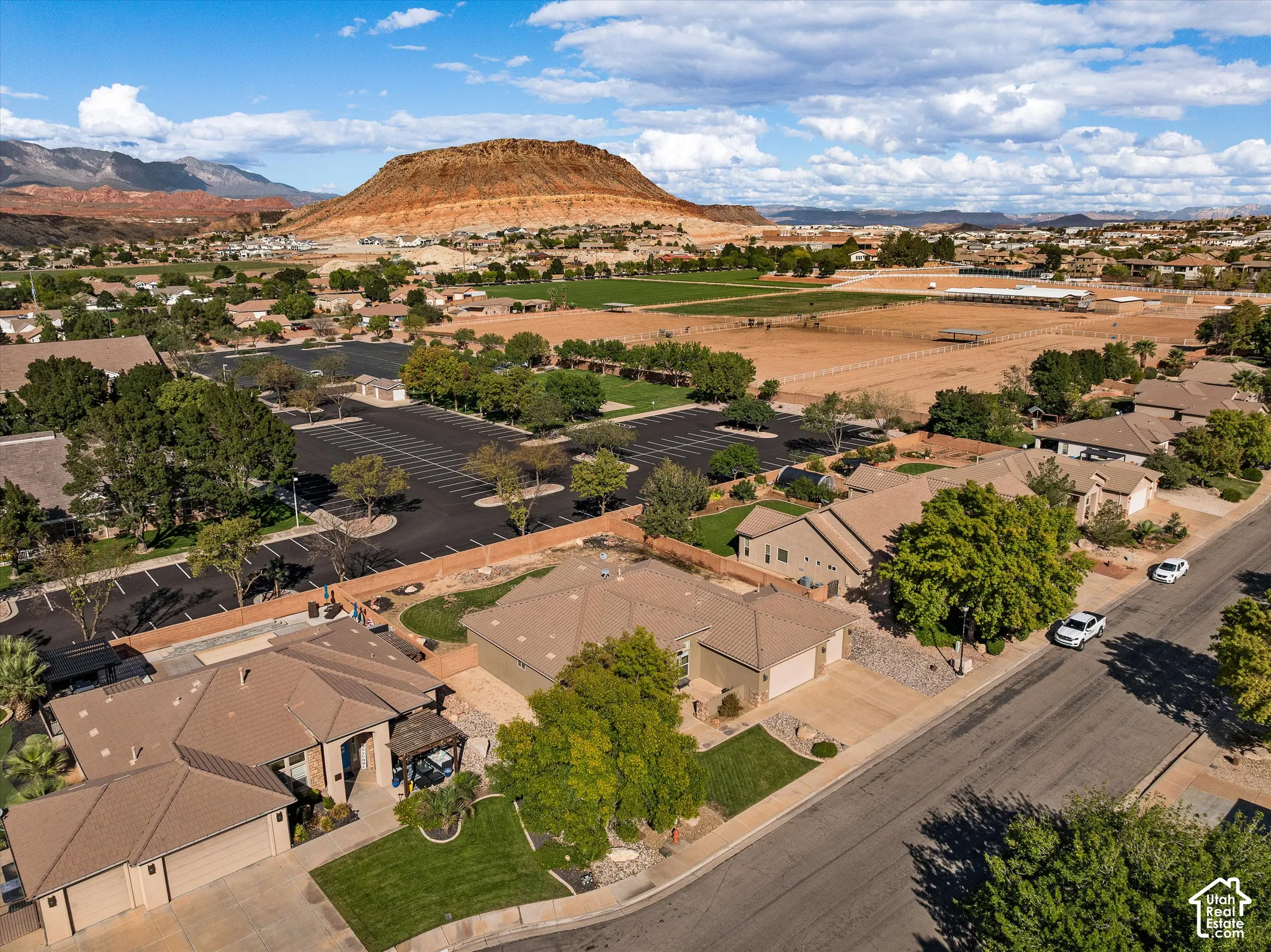 Aerial perspective of residential properties featuring tile roofing, multi-car garages, concrete driveways, and expansive mountain backdrops