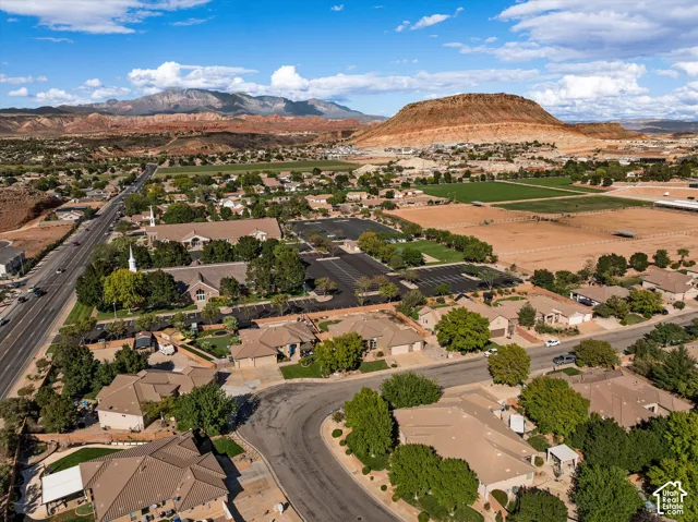 Aerial perspective featuring extensive desert terrain, prominent mountain topography, and established residential landscaping