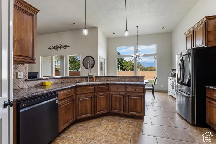 Kitchen featuring stained wood cabinetry, stone-finish countertops, tile flooring, high ceilings, and pendant lighting