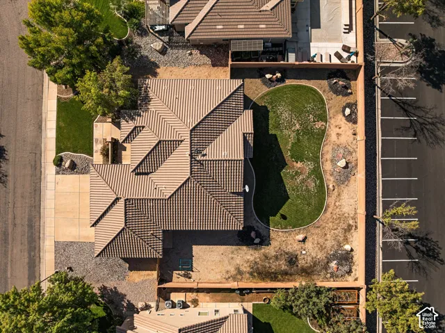 Aerial perspective featuring a tile roof, concrete driveway, fenced yard, lawn area, and gravel landscaping