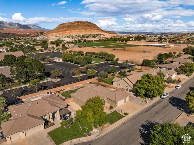 Aerial perspective of residential properties featuring tile roofing, multi-car garages, concrete driveways, and expansive mountain backdrops