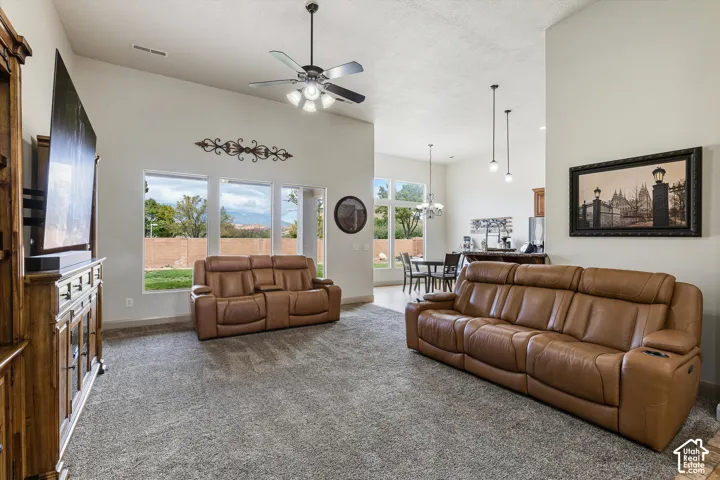 Vaulted ceilings, expansive windows, overhead ceiling fan with light kit, and dual pendant lighting fixtures