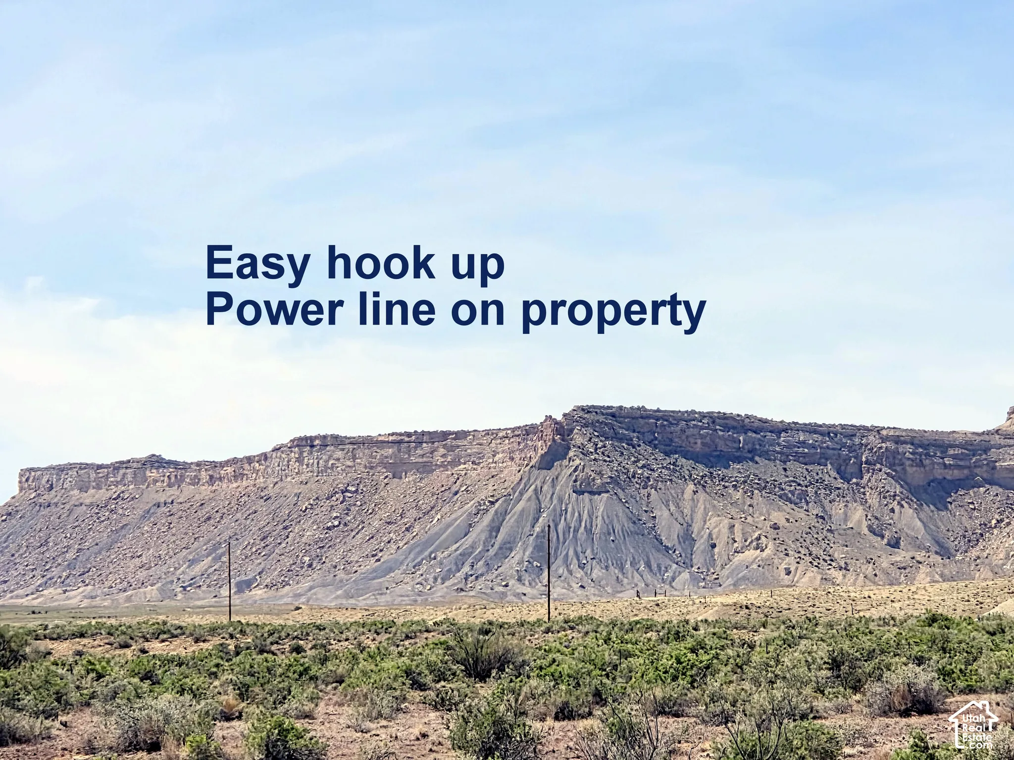 Expansive open acreage featuring utility poles and rugged mountain topography