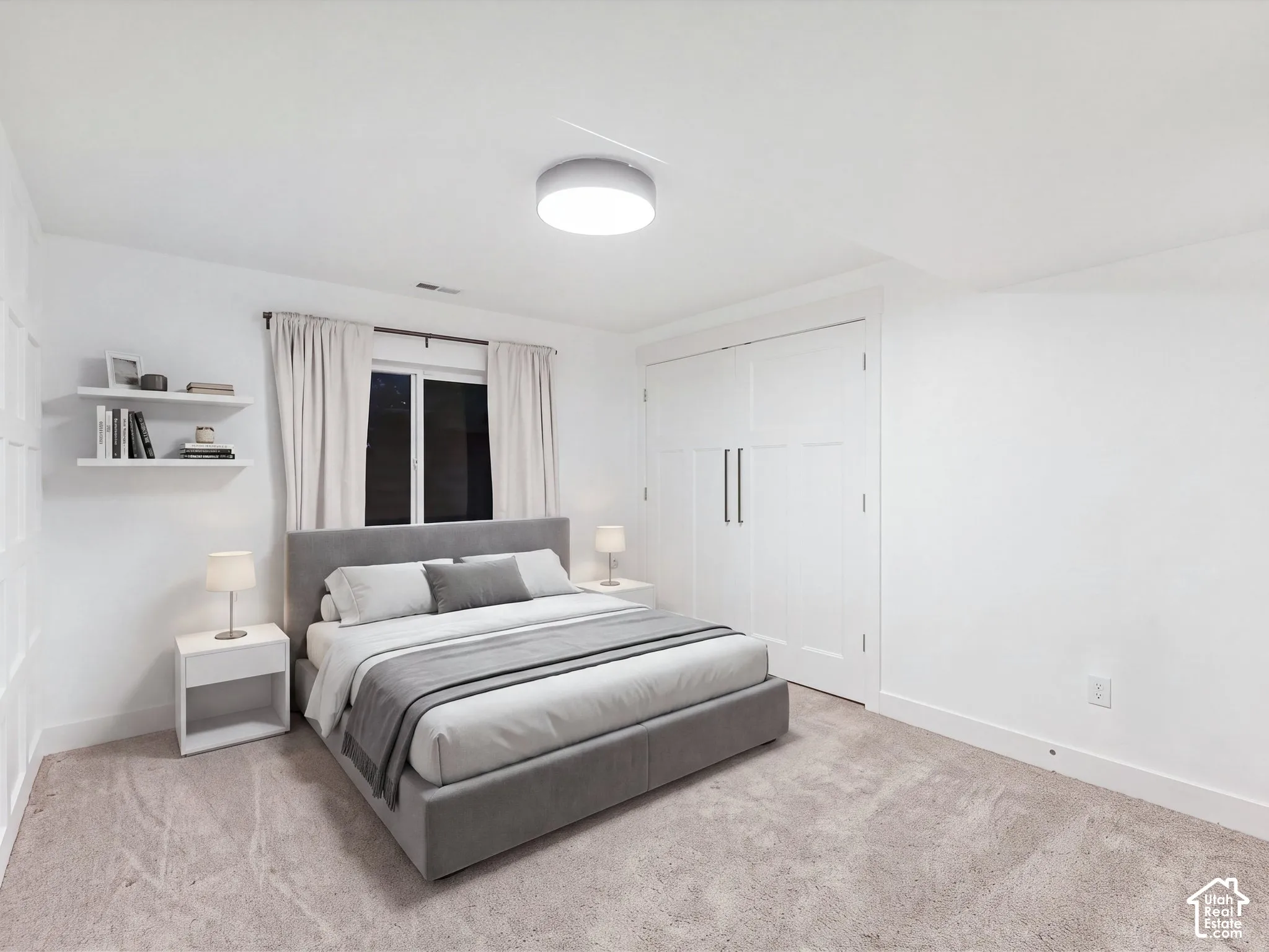Bedroom featuring wall-to-wall carpeting, flush-mount circular lighting, double-door closet with vertical pulls, and integrated floating shelving