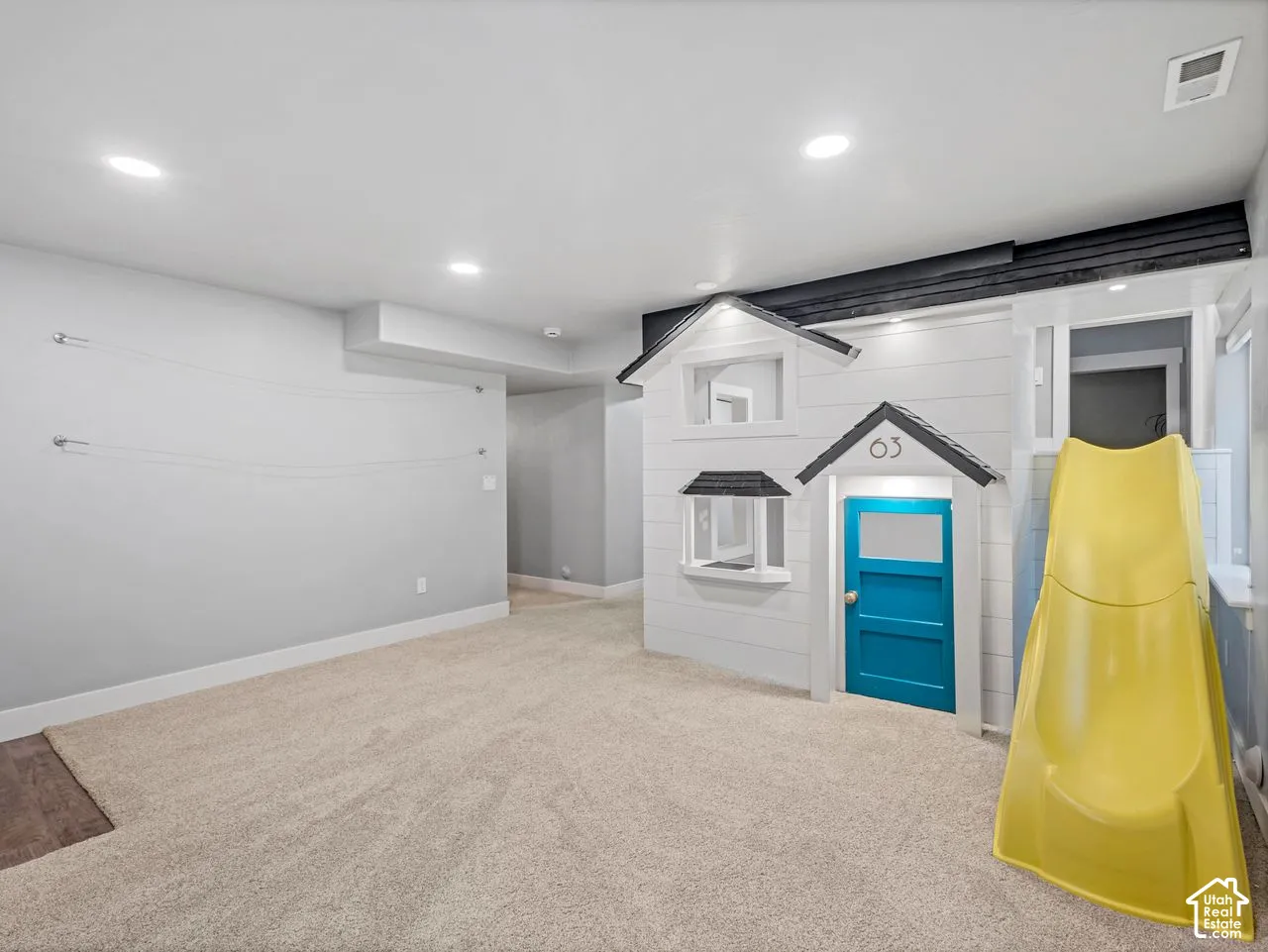 Multi-purpose room featuring neutral carpeting, recessed lighting, and a custom built-in architectural structure with an integrated slide