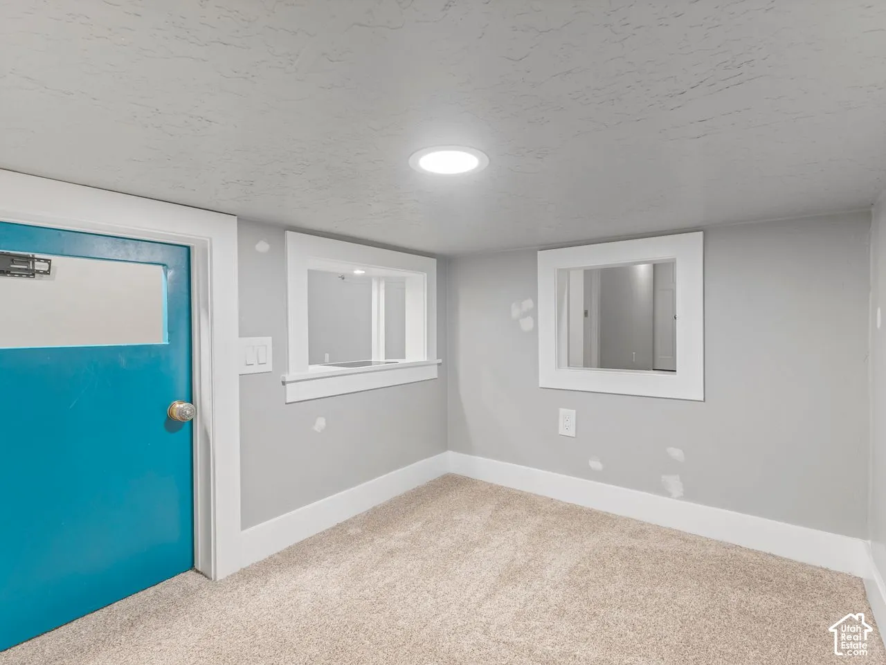 Interior space featuring wall-to-wall carpeting, two interior wall openings with white trim, a recessed ceiling light, and a solid-core door with a blue finish