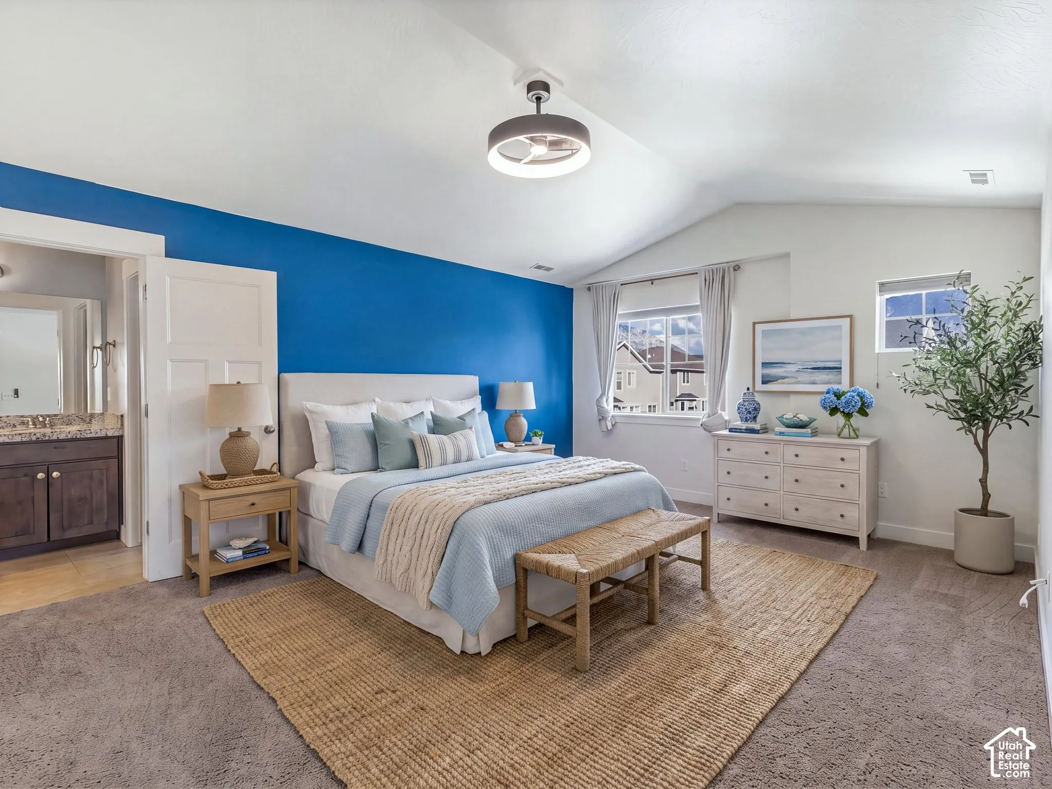Vaulted ceilings, bedroom featuring a prominent blue accent wall, neutral carpeting, and a modern ceiling fan with integrated lighting