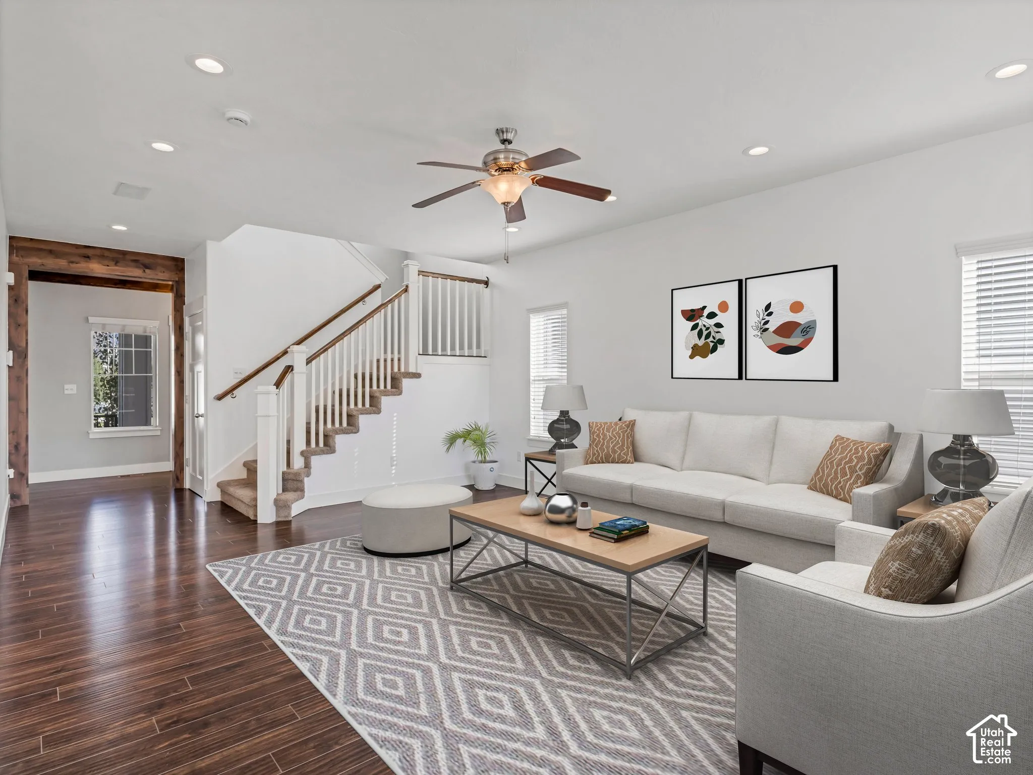 Living area featuring wood-finish flooring, recessed lighting, a ceiling fan, and a staircase with a wooden handrail and white balusters