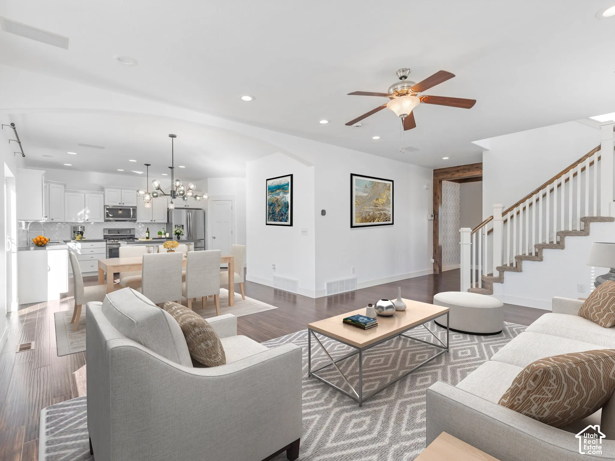 Open-concept floor plan featuring wood-finish flooring, recessed lighting, a multi-bulb statement chandelier, and a wood-accented doorway