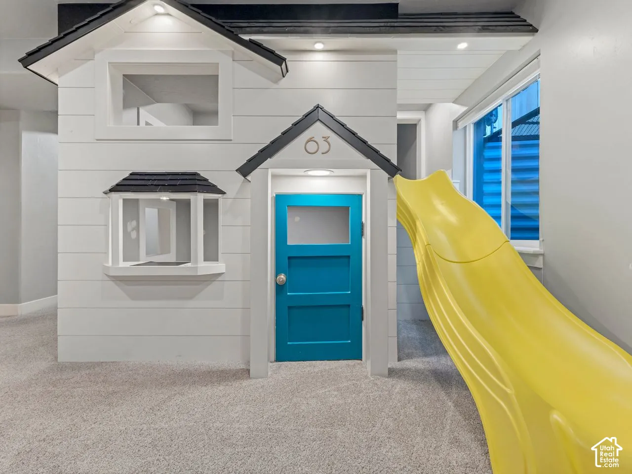 Custom built-in structure featuring white horizontal paneling, a gabled roofline, a bay window, and a built-in slide