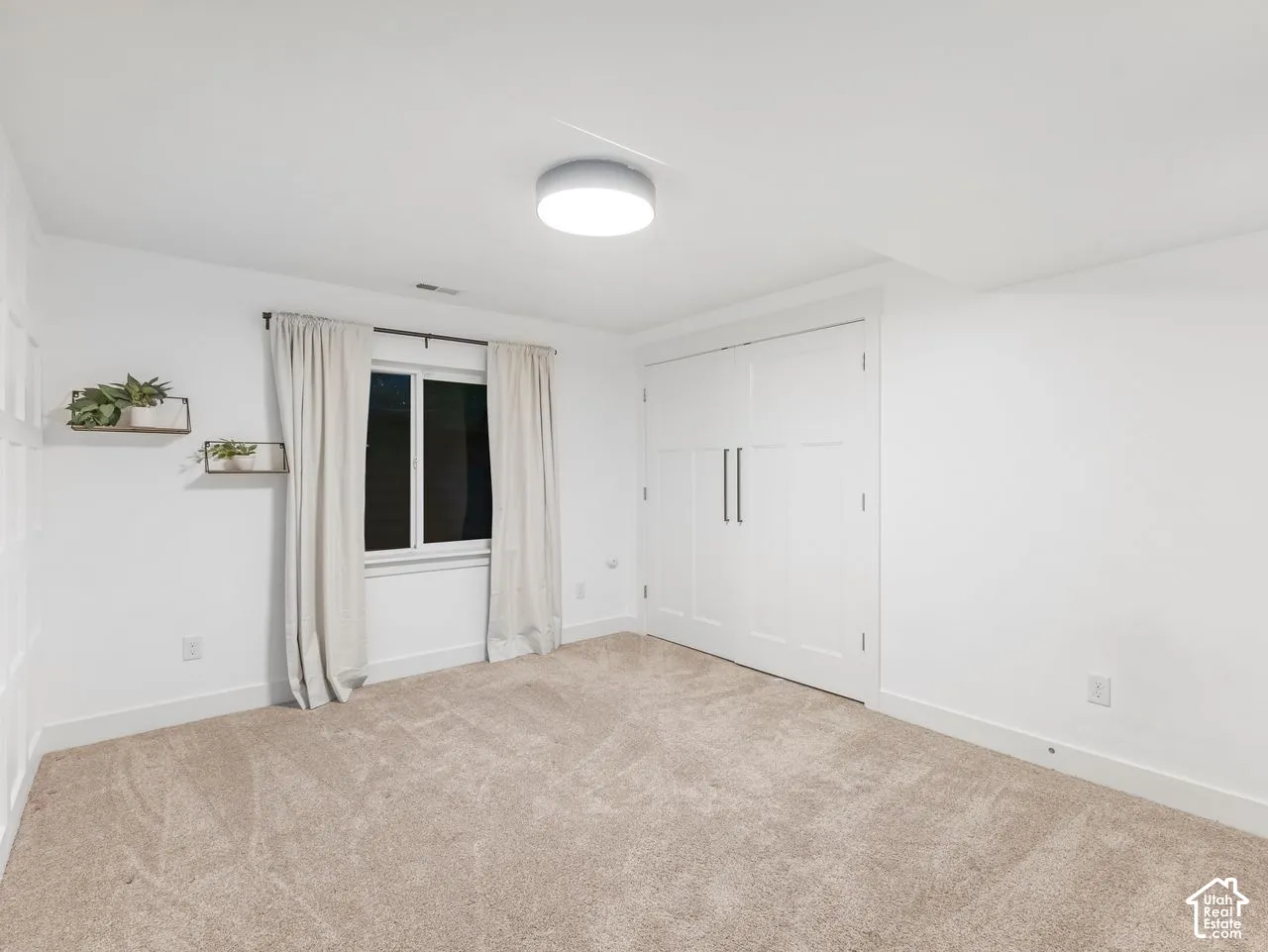 Room featuring wall-to-wall carpeting, dual-door closet with vertical hardware, window, and flush-mount ceiling lighting