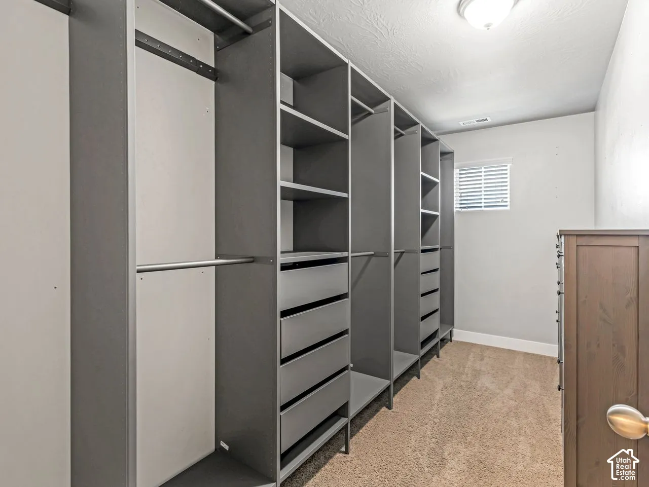 Custom floor-to-ceiling closet organization system featuring adjustable shelving, multiple pull-out drawers, and hanging rods