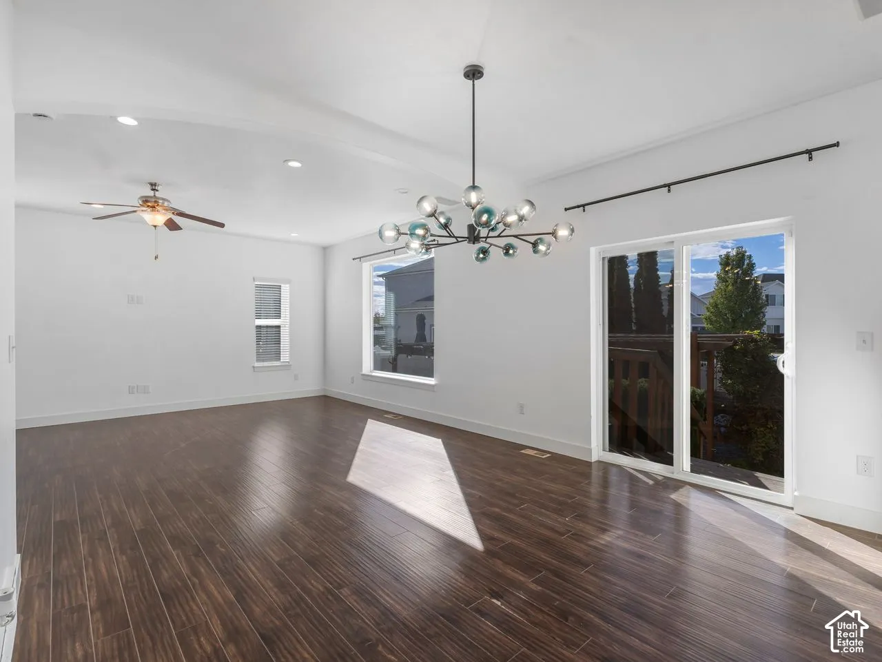 Vaulted ceilings, wood-finish flooring, multi-globe chandelier, recessed lighting, and sliding glass doors