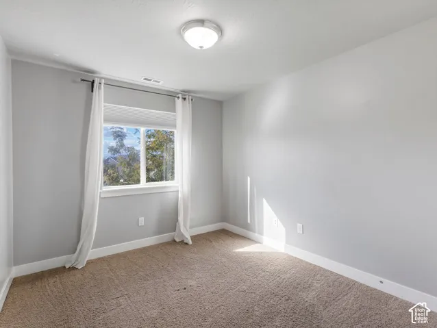 Neutral wall tones, carpeted flooring, and a single-pane sliding window with a minimalist flush-mount ceiling fixture