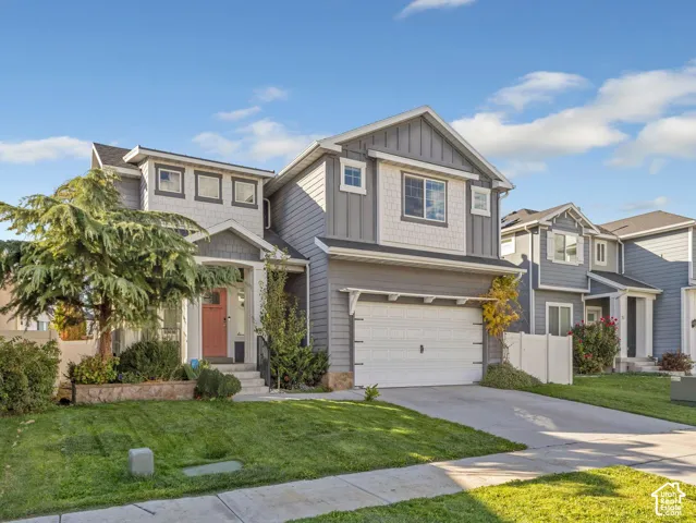 Two-story exterior featuring fiber cement siding, a stone veneer foundation, multi-textured gables, a two-car garage, and a covered front entryway