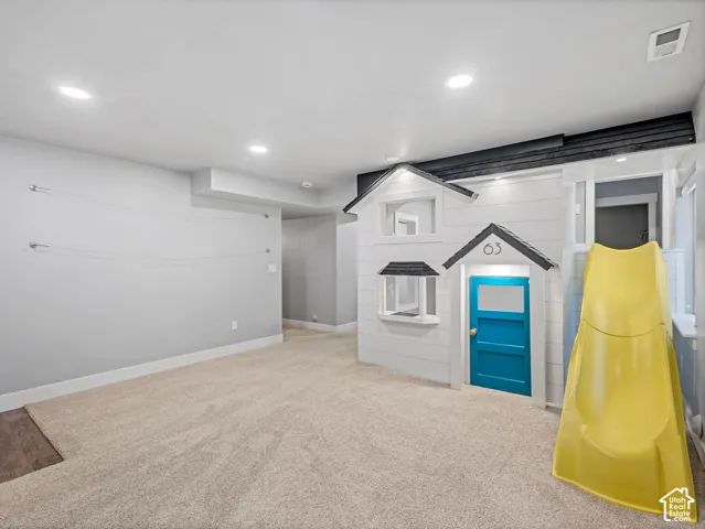 Multi-purpose room featuring neutral carpeting, recessed lighting, and a custom built-in architectural structure with an integrated slide