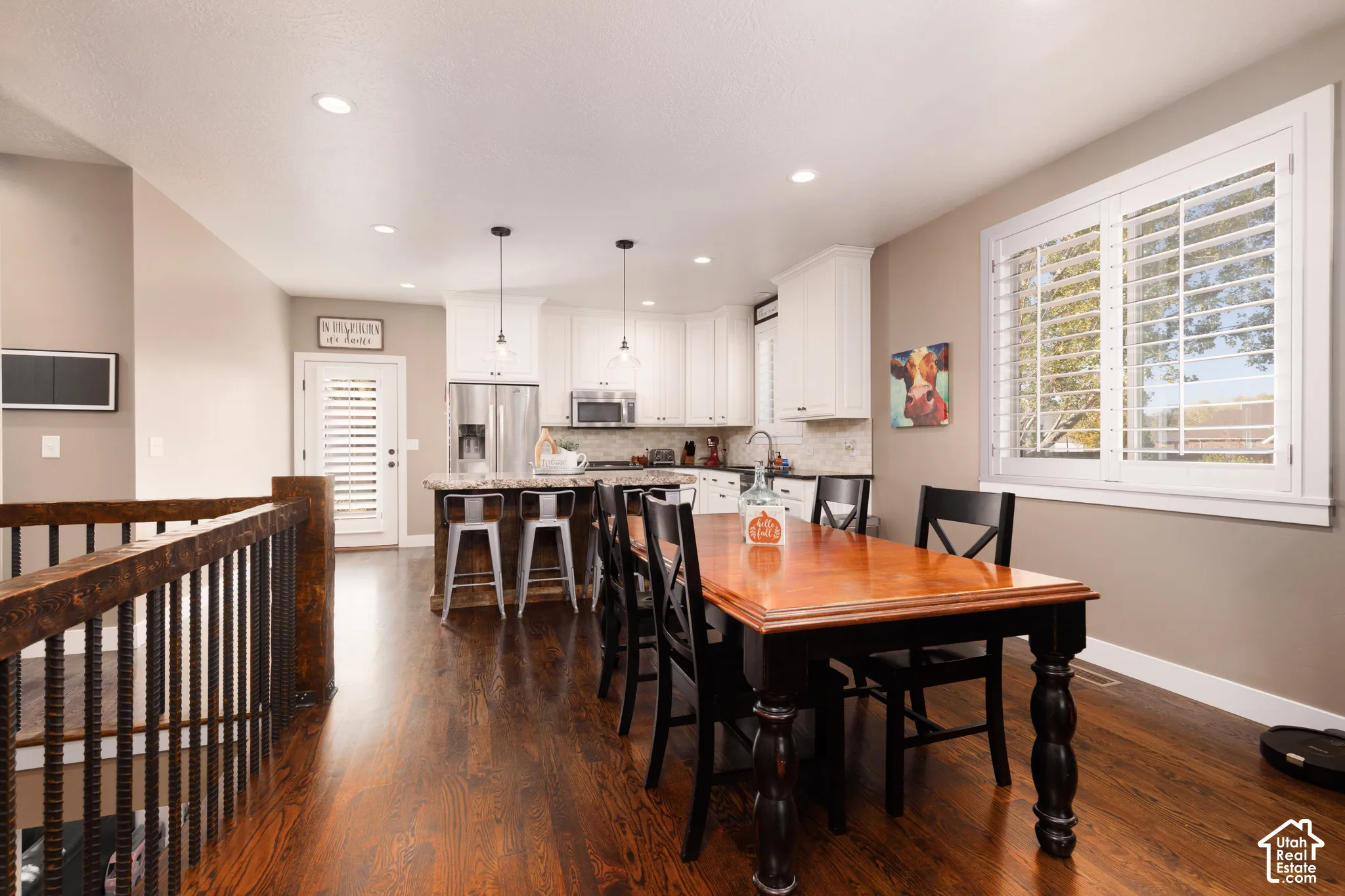 Kitchen featuring white cabinetry, stone countertops, stainless steel appliances, wood-finish flooring, and window plantation shutters