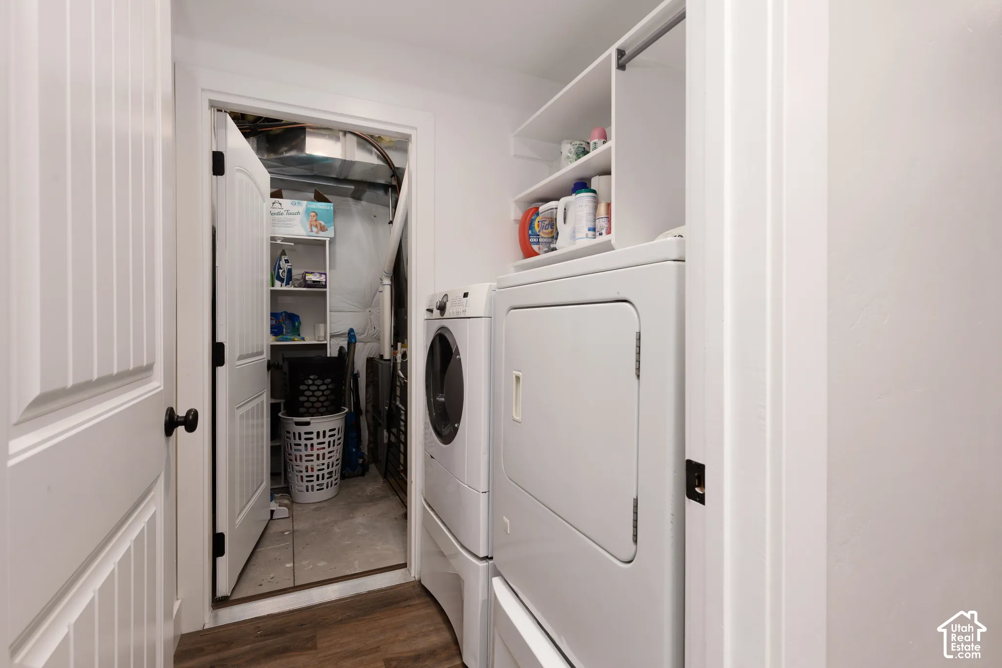 Laundry room featuring wood-finish flooring, built-in overhead shelving, and a panel-style interior door