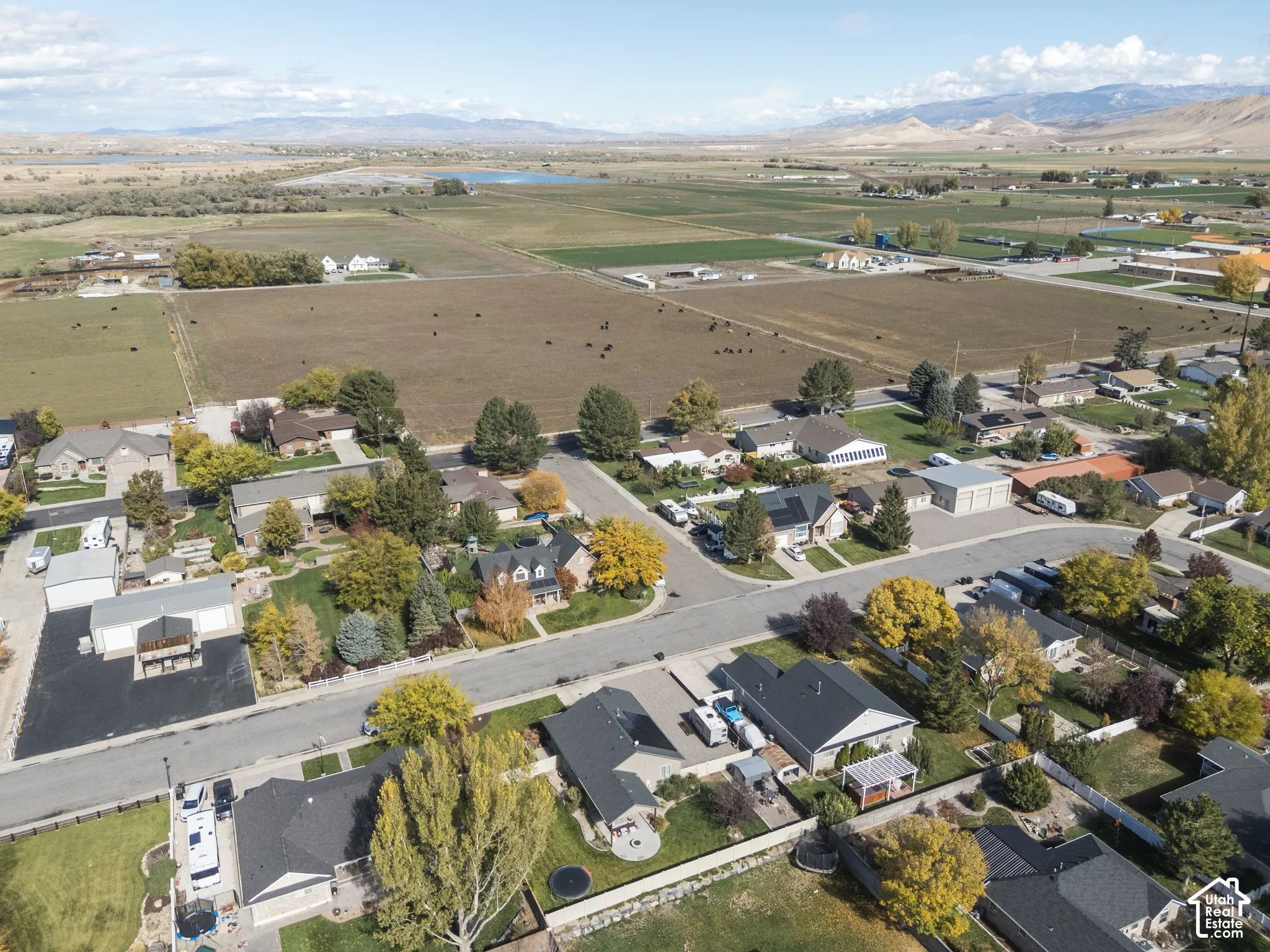 Aerial perspective featuring residential lots, paved streets, established landscaping, and a backdrop of mountain ranges