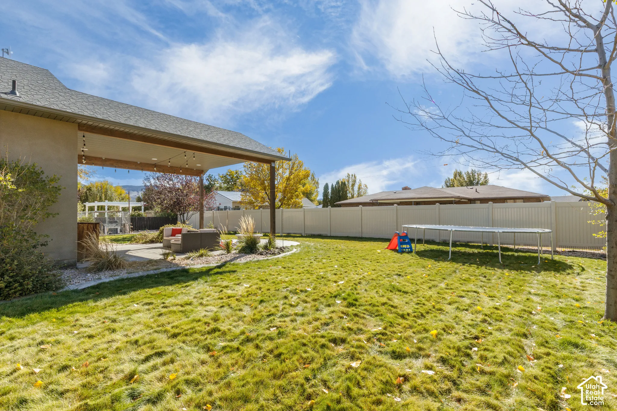 Backyard featuring a covered concrete patio, solid vinyl privacy fencing, and a manicured lawn