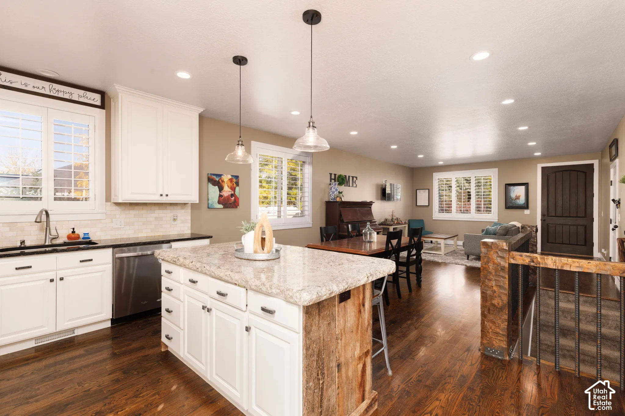 Kitchen featuring a center island with a natural stone countertop, white shaker-style cabinetry, recessed lighting, pendant fixtures, and wood-finish flooring
