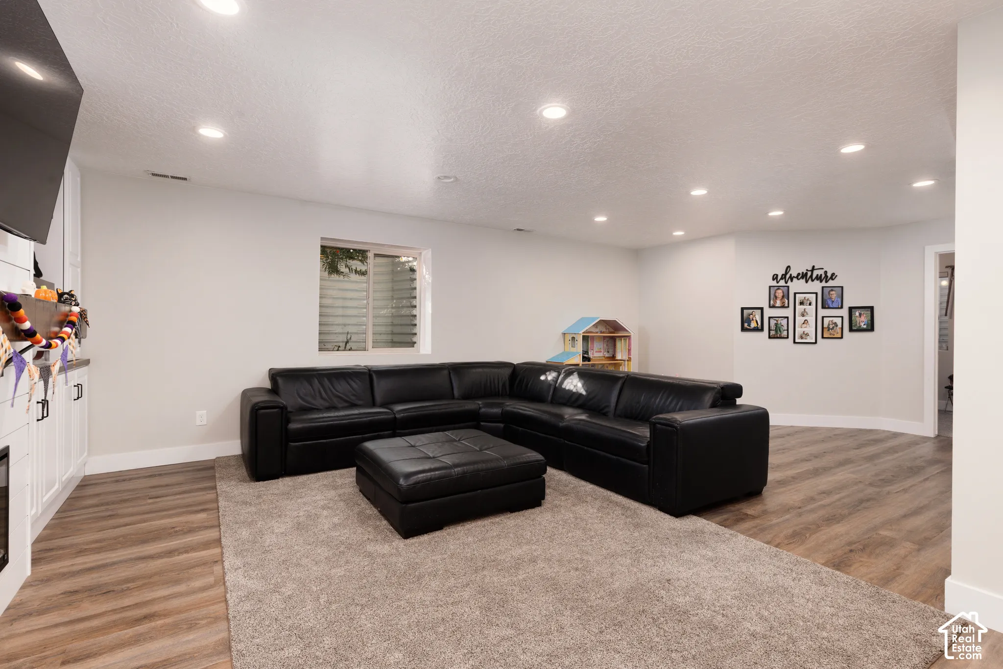 Living area featuring wood-finish flooring, recessed lighting, and built-in white cabinetry