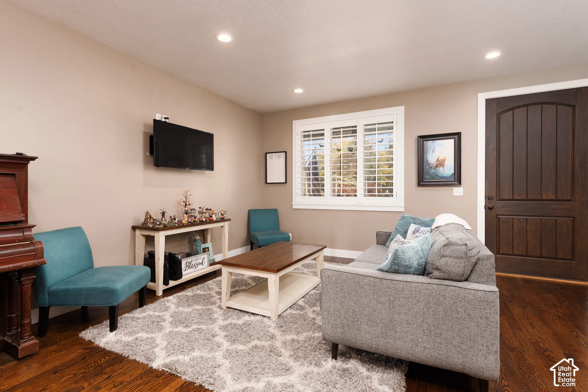 Interior room featuring wood-finish flooring, recessed lighting, white plantation shutters, and a stained wood door with an arched top panel