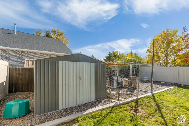 Backyard featuring a metal storage shed, chain-link enclosure, and perimeter vinyl fencing