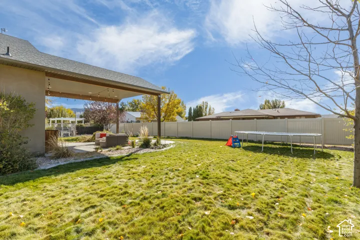 Backyard featuring a covered concrete patio, solid vinyl privacy fencing, and a manicured lawn