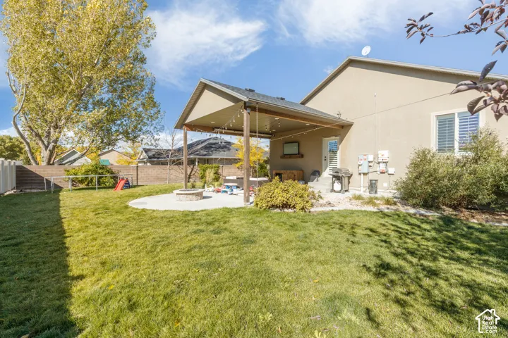 Backyard featuring a covered patio, concrete hardscaping, stone fire pit, and enclosed fencing