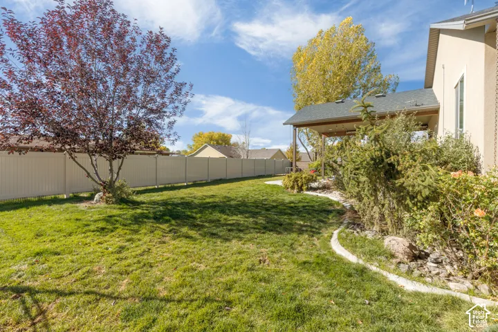 Backyard featuring a covered patio, vinyl privacy fencing, manicured lawn, and mature landscaping