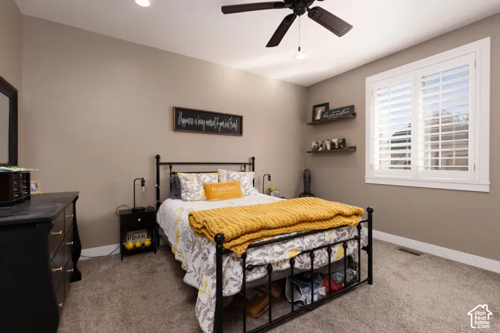 Room featuring neutral-toned walls, carpeting, white plantation shutters, and a ceiling fan