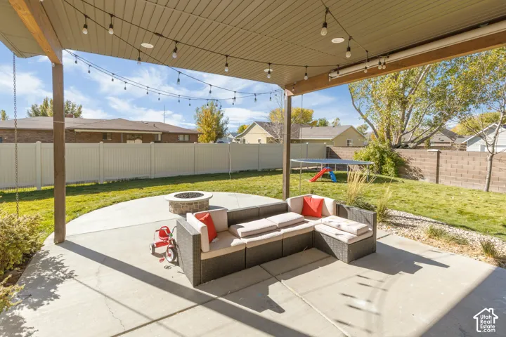 Covered patio featuring a concrete slab foundation, stone-finish fire pit, and privacy fencing enclosing the grounds