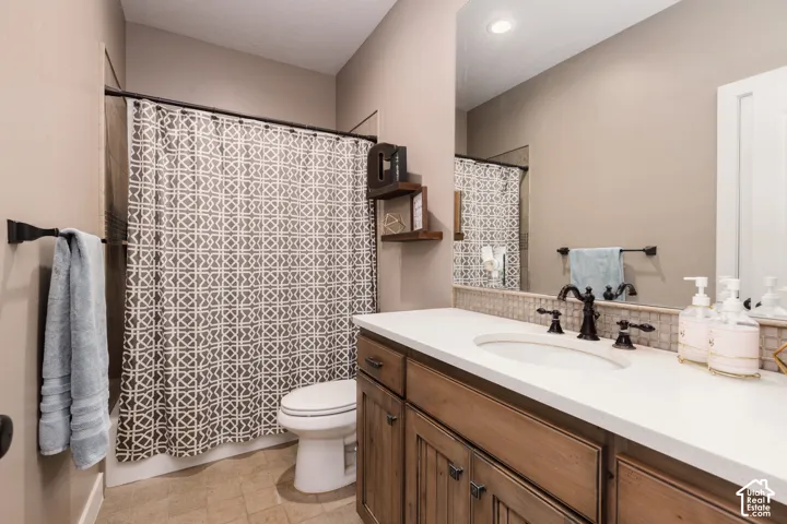 Bathroom featuring a vanity with wood-finish cabinetry, a white countertop, an integrated oval sink, and a multi-piece faucet
