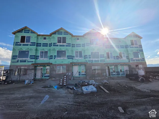 Three-story building exterior featuring a structural frame with exterior sheathing, multi-gabled roofline, and installed window frames